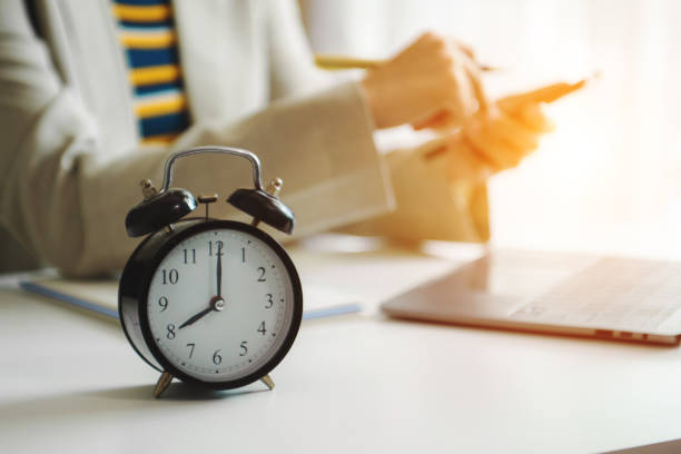 istock Alarm clock on the desk. Business hand using smartphone, laptop and tablet  working in modern office building 1736765423