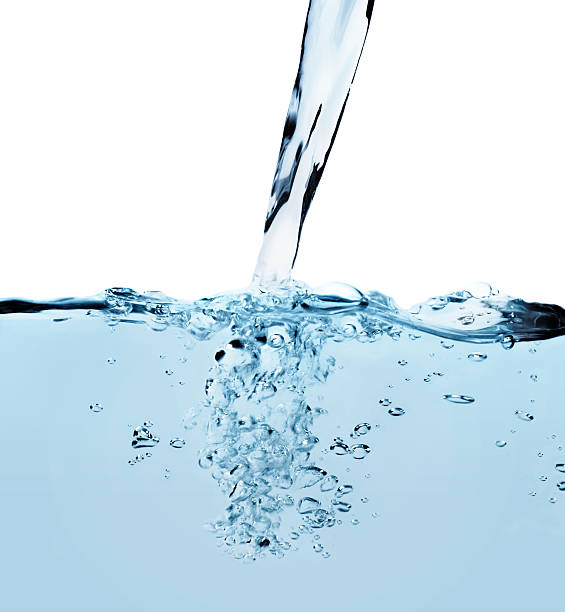 Pouring liquid Blue tinted water being poured, showing bubbles and motion. pouring stock pictures, royalty-free photos & images