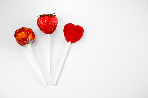 3 Strawberry-Lollypops, strawberry fruit, strawberry flavor and lollypop heartshaped, white background, horizontal, free space