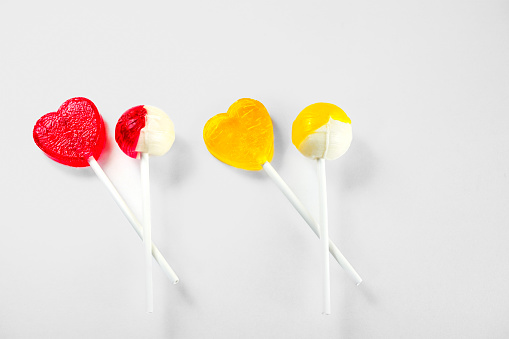 4 Lollipops red and yellow, heart-shaped and round, white background, horizontal