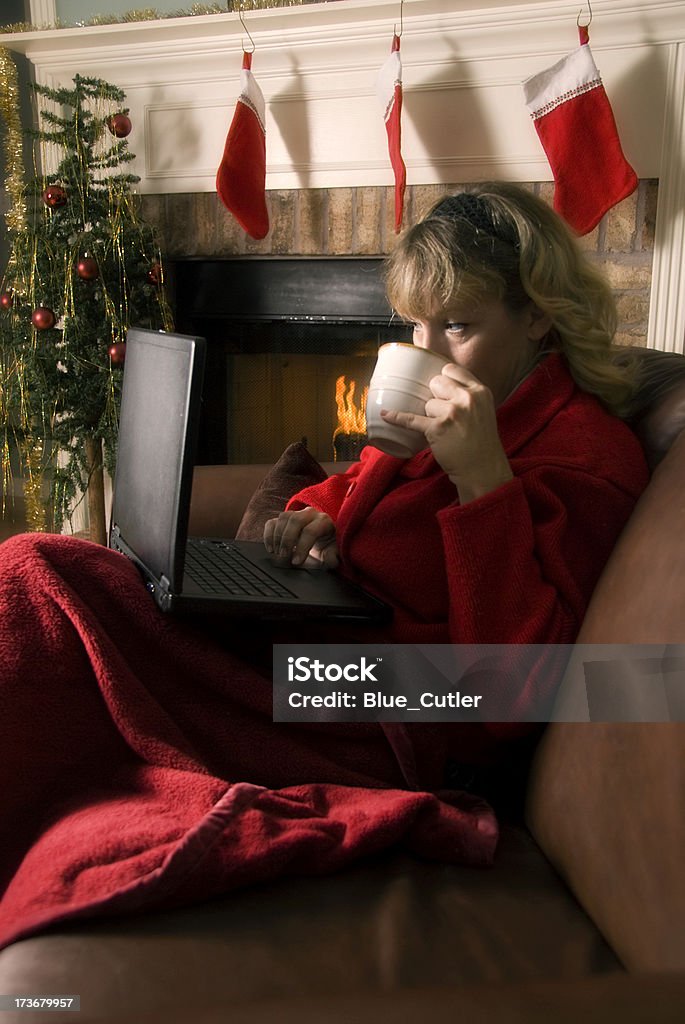 Femme sur ordinateur portable près de la cheminée au moment de Noël - Photo de Chocolat chaud libre de droits