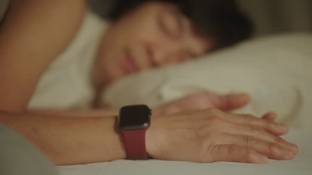 Mature woman wearing smart watch while sleep at night.