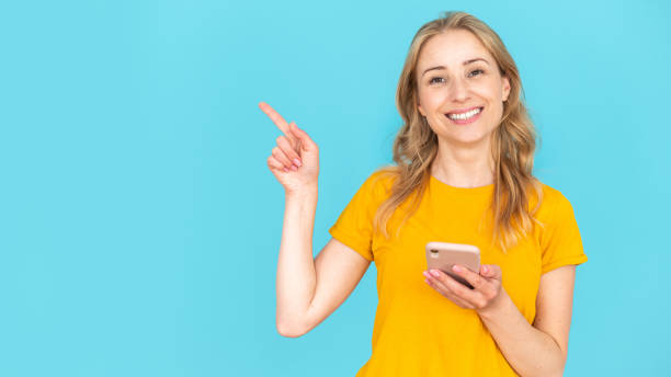 istock Satisfied woman holding smartphone and pointing up in copy space 1736801332