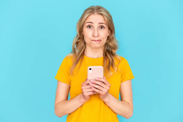 istock Unsure woman use cellphone, standing isolated on blue copy space background 1736801333