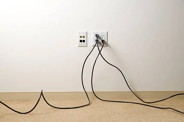 Electrical extensions chords plugged into wall in an office space.