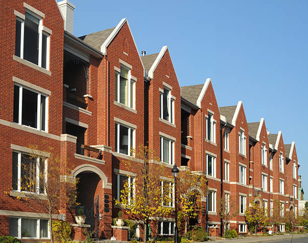 Low angle view of a brick building with large balconies against a blue sky.