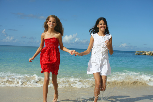 Two sisters (10 and 12) running on the beach. Caribbeans.