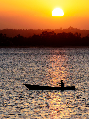 A dugout canoe paddles by as the sun sets off Zanzibar.