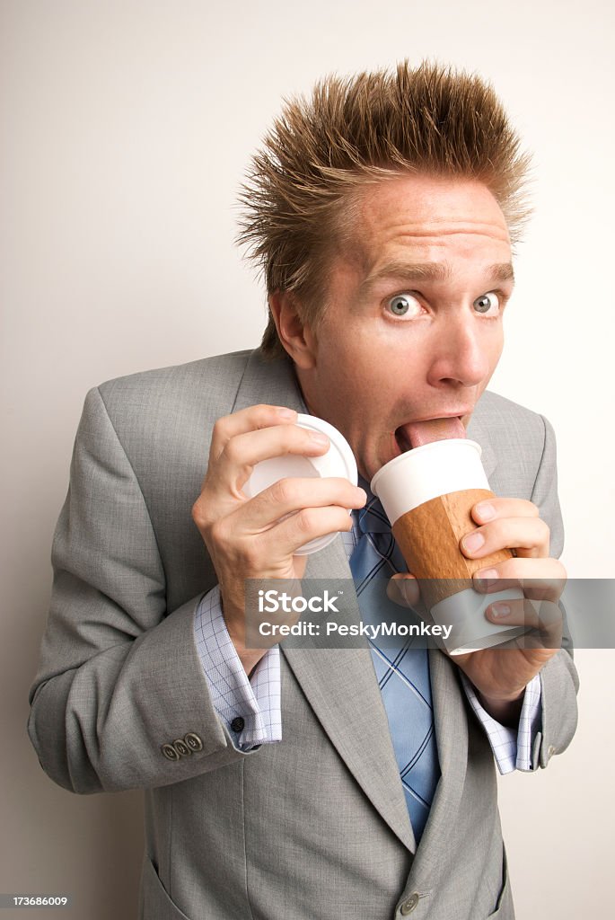 Jeune homme victime de la caféine Homme d'affaires boire du café lécher Cup - Photo de Cheveux dressés sur la tête libre de droits