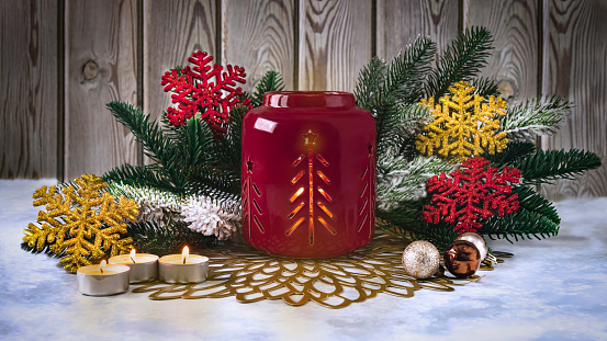 Atmospheric Christmas ceramic candle holder with candles, with fir branches, Christmas balls and decorative snowflakes. Festive composition, Merry Christmas concept