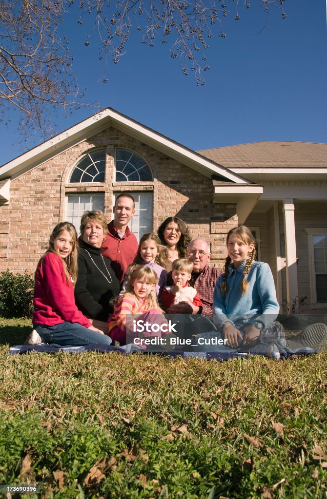 Multi-generational family sitting on front lawn A Multi-generational family sitting on front lawn of a houseMore in this series can be found here: Family Stock Photo