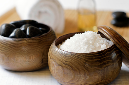 Bath salts, massage stones, and massage oil in a zen spa atmosphere. 