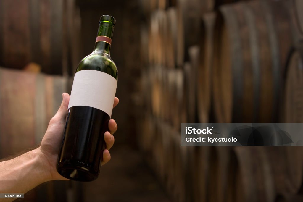 Selezionando una bottiglia presso la cantina - Foto stock royalty-free di Bottiglia di vino