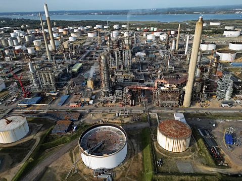Chimneys of biggest UK oil refinery and petrochemical complex in Fawley, Hampshire. Aerial view on rusty oil storage tanks and oil industry.