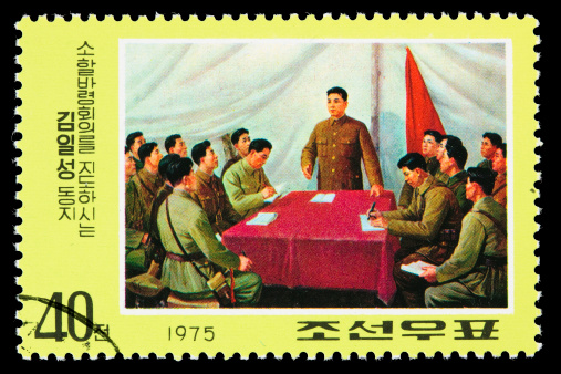 A 1975 North Korean postage stamp with an illustration of President Kim Il-Sung conducting a military meeting. DSLR with macro lens; no sharpening. Korean text translation: Comrade Kim Il-Sung conducting a meeting on jurisdiction orders.