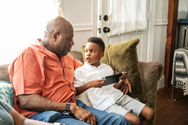 Young Black boy playing video game with grandfather