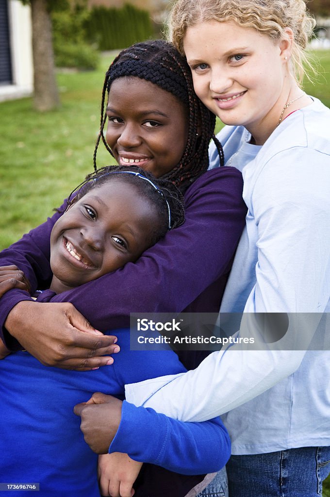 Três meninas feliz abraçando do lado de fora - Foto de stock de Amizade royalty-free