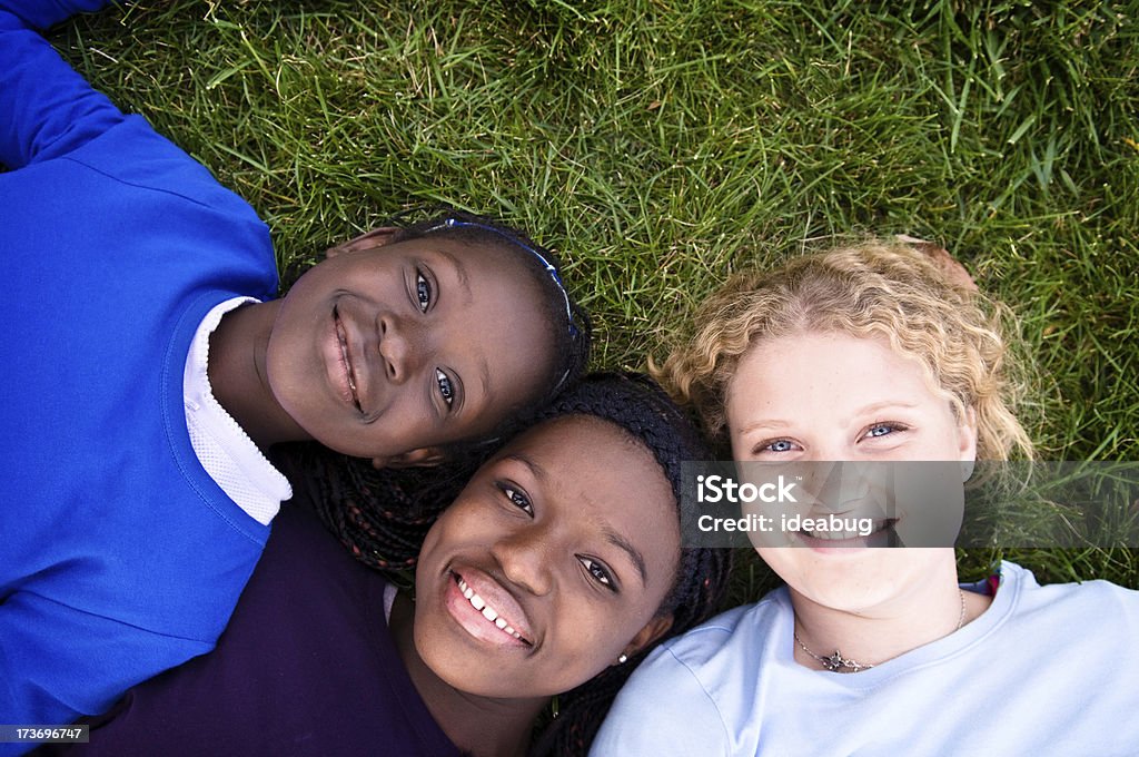 Três meninas feliz deitado na grama - Foto de stock de Adolescentes Meninas royalty-free