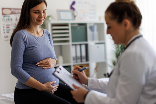 Shot of a female doctor going over paperwork with a pregnant patient