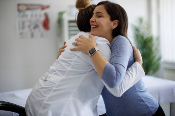 Scatto di una donna incinta che abbraccia il suo medico durante una consultazione - foto stock