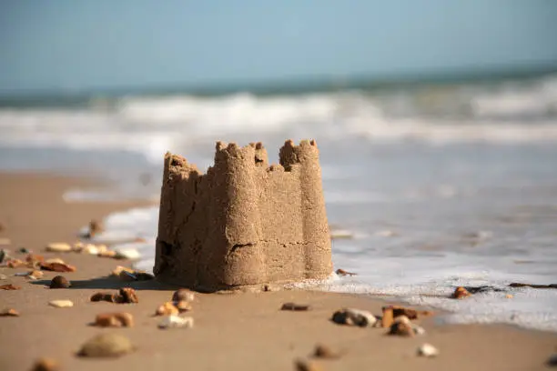 sandcastle being washed away on the beach. shallow DOF.