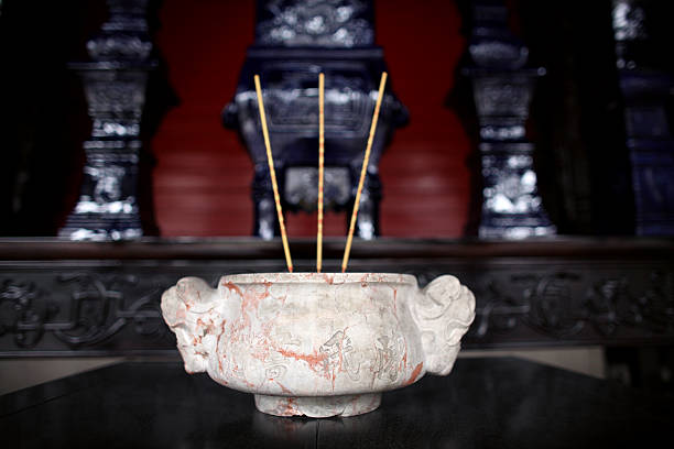 A Chinese incense burner filled with burned out candles and incense