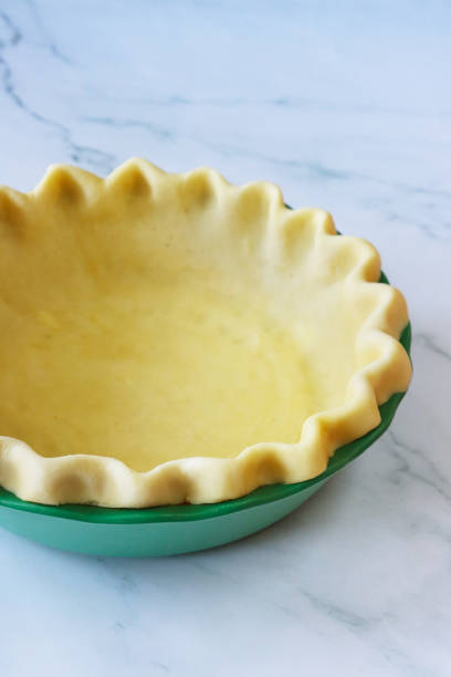 istock Image of pastry dough lined tart tin case, freeform fluted pie crust, preparation for baking pie, homemade pastry made of white flour, marble effect background, elevated view, focus on foreground 1737066340