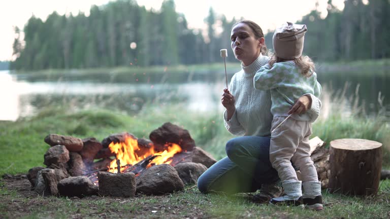 Family camping at lake, roasting marshmallows on campfire.