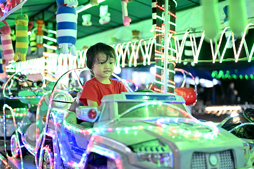 Asian toddler driving a toy car