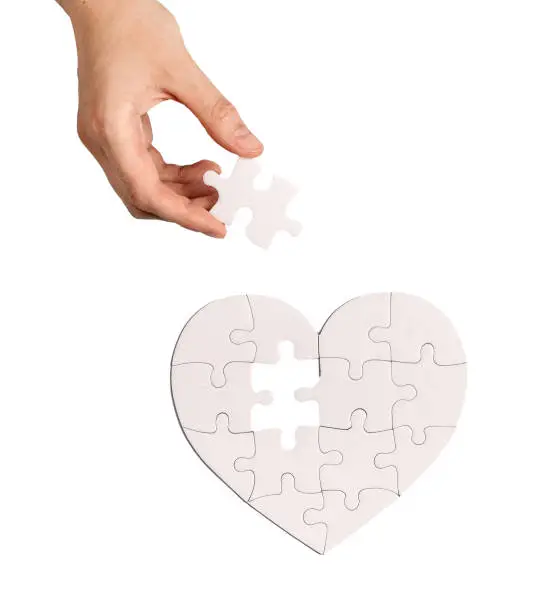 Photo of Adding last puzzle piece to complete jigsaw, love heart