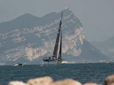 TF35 class catamaran of the  Ylliam XII - Comptoir Immobilier team and sailing at a tilt. Foils visible above the water. Malcesine Cup 09/2023. Malcesine, Italy.