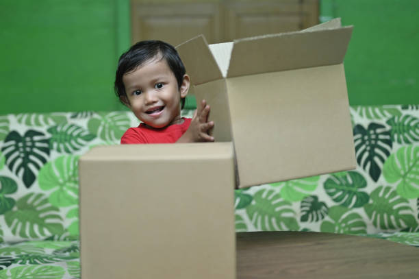 Recycling. Cute little boy with cardboard box full of different waste paper on green background