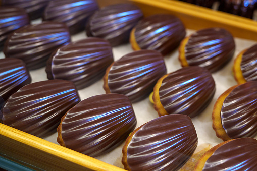 Chocolate madeleine cakes are displayed in a bakery store