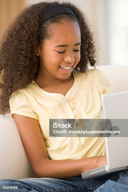 Foto de Jovem Garota Usando O Laptop Na Sala De Estar E Sorrindo e mais fotos de stock de Afro-americano