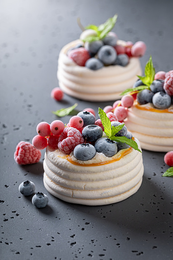 Creamy mini Pavlova dessert with frozen fruit and whipped cream. Pavlova dessert with frozen blueberries and raspberries.