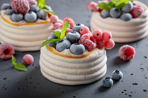 Sweet mini Pavlova dessert with frozen fruit and whipped cream. Pavlova dessert with frozen blueberries and raspberries.