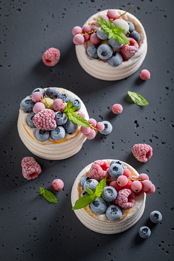 Homemade mini Pavlova dessert made of mascarpone and frozen berries. Pavlova dessert with frozen blueberries and raspberries.