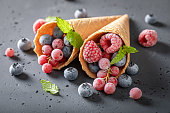 Sweet sorbet with frozen berries in cone.