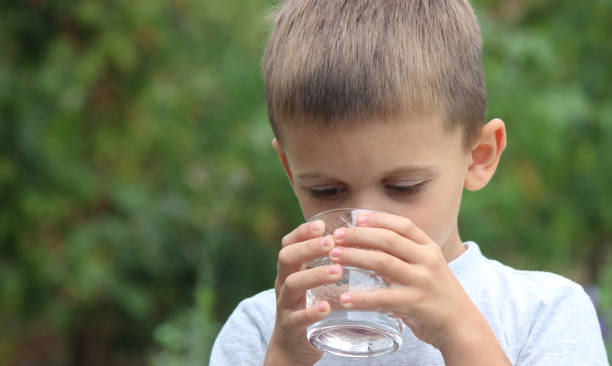 istock a boy drinks water from a glass in nature. Selective focus 1737138705