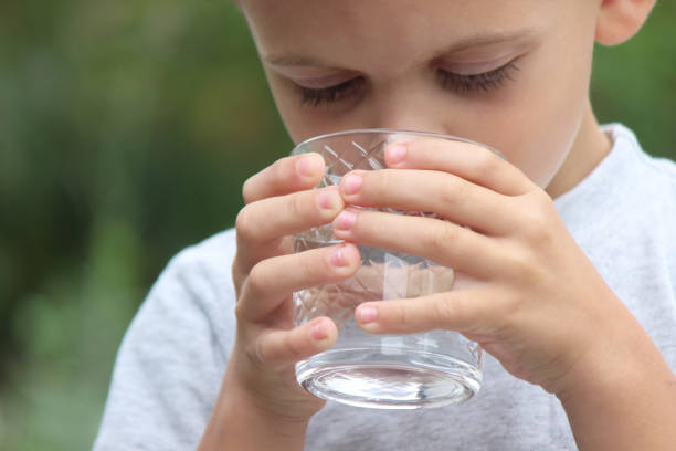 istock a boy drinks water from a glass in nature. Selective focus 1737138715