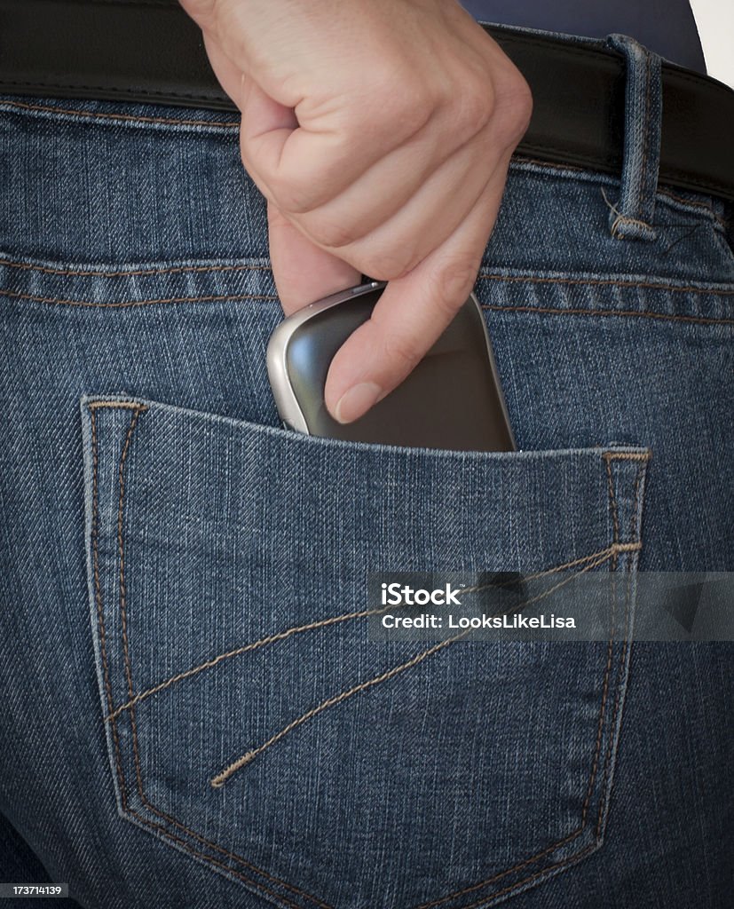 Hand pulling smartphone out of a pocket Hand pulling a cell mobile smart phone out of the back jeans pocket Blue Stock Photo