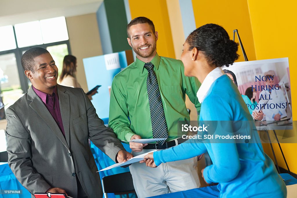 Jovem profissional enviar currículo para a equipe de negócios na Feira de emprego - Foto de stock de Feira de emprego royalty-free