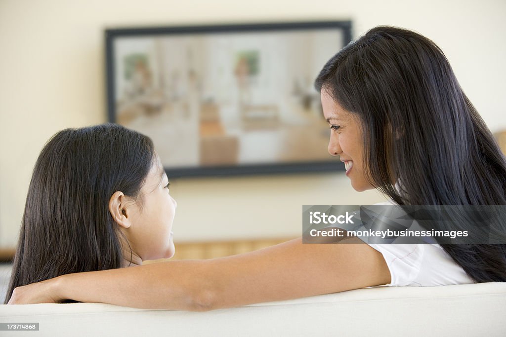 Mulher e menina na sala de estar com TV de tela plana - Foto de stock de Assistir TV royalty-free