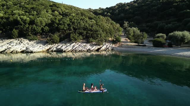 Beautiful beaches and coast of Ionian island and three women enjoying on stand up paddle (SUP) board