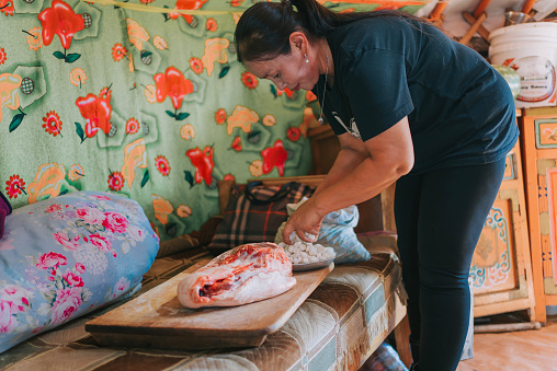 Mongolian woman cutting lamb meat preparing buuz