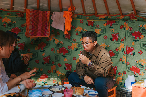 solo travel Asian Chinese man trying homemade butter with bread inside Mongolian yurt