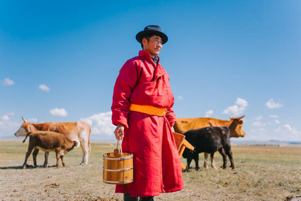 mongolian man carrying milk bucket looking away standing on pasture - independent mongolia fotos imagens e fotografias de stock