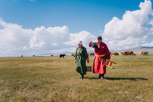 Happy Mongolian couple walking back to yurt after milking cow