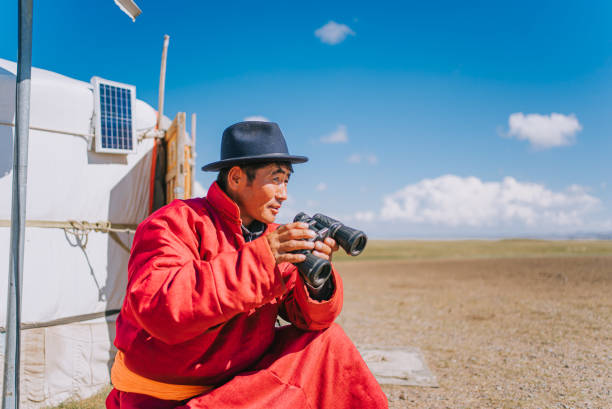 istock Mongolian nomadic man grazing watching flock of sheeps with binoculars in front of yurt 1737181798