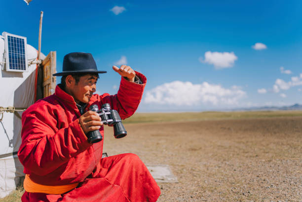 istock Mongolian nomadic man grazing watching flock of sheeps with binoculars in front of yurt 1737181834